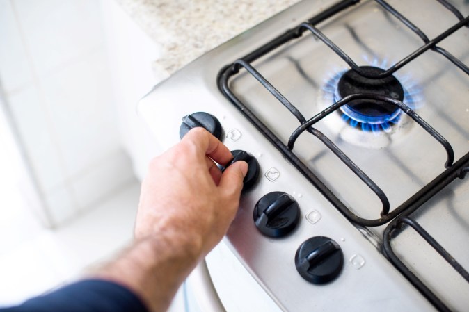 Person turning on gas stove.