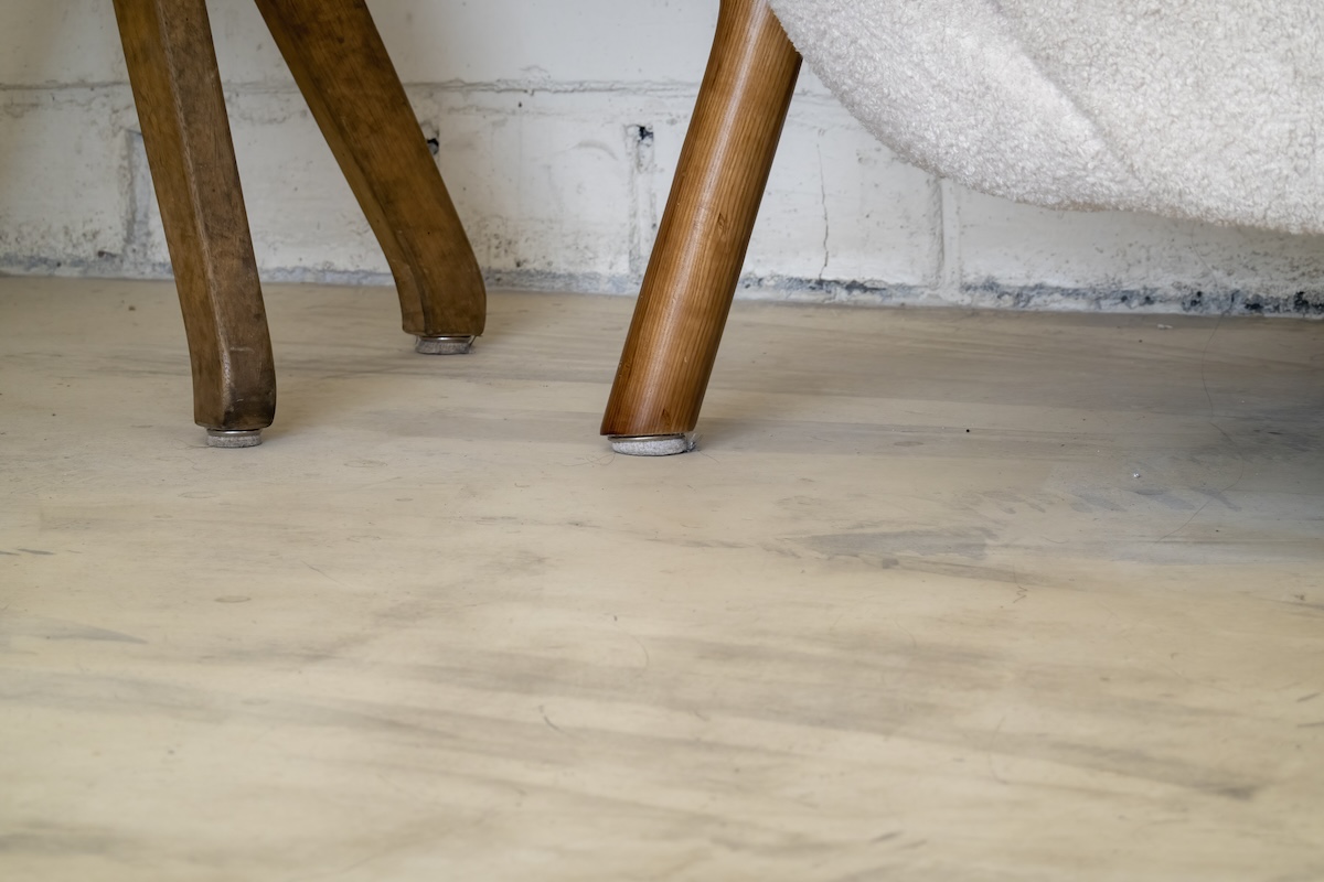 A sofa with small legs capped with protective felt pads to prevent scratches on the wooden floor it rests on.