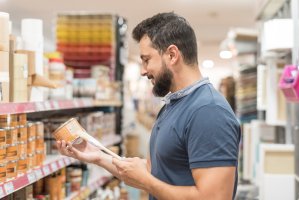 Bearded man in craft store selecting paint.