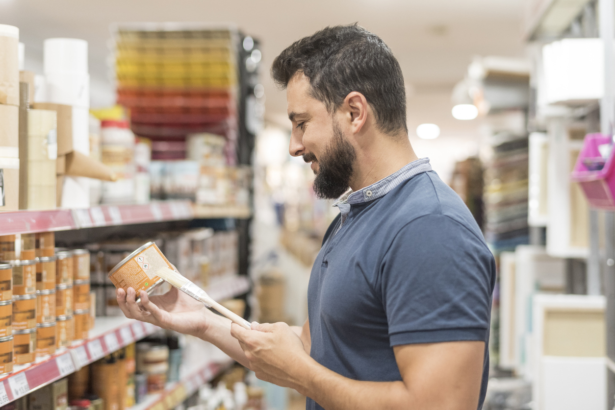 Bearded man in craft store selecting paint.