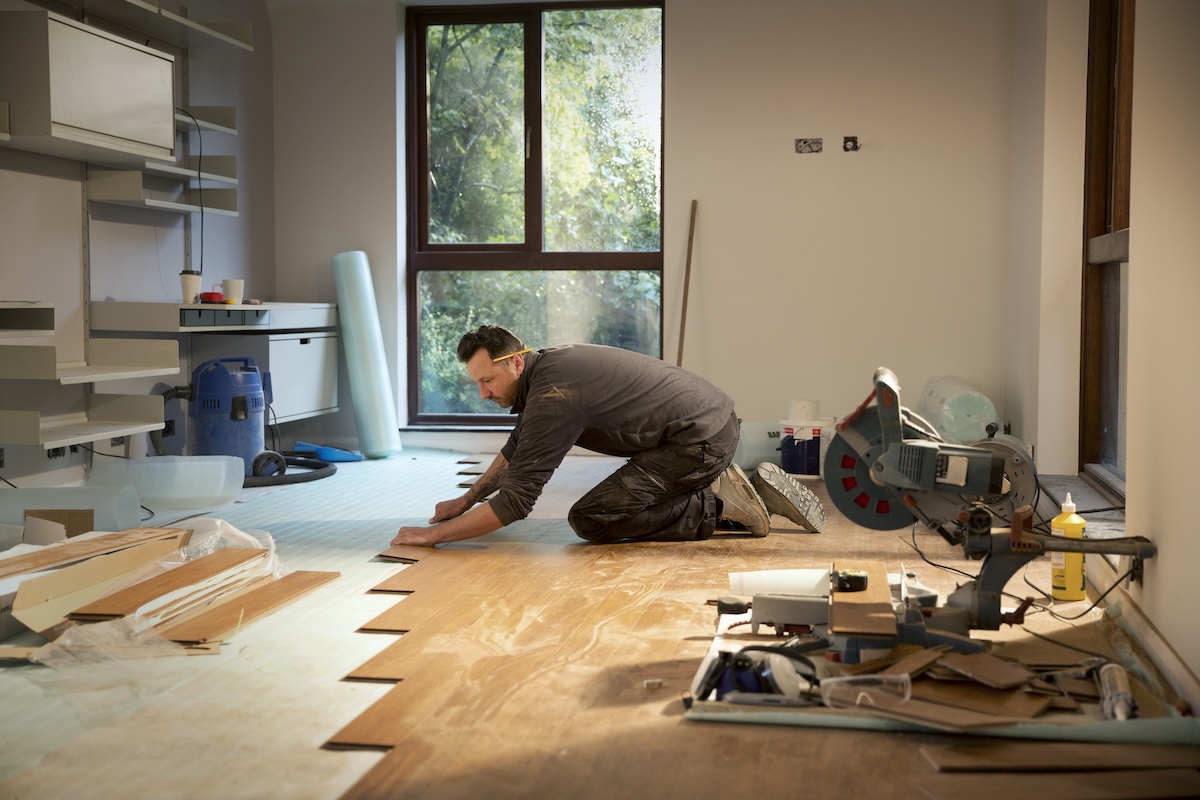 A carpenter lays hardwood flooring into a home.