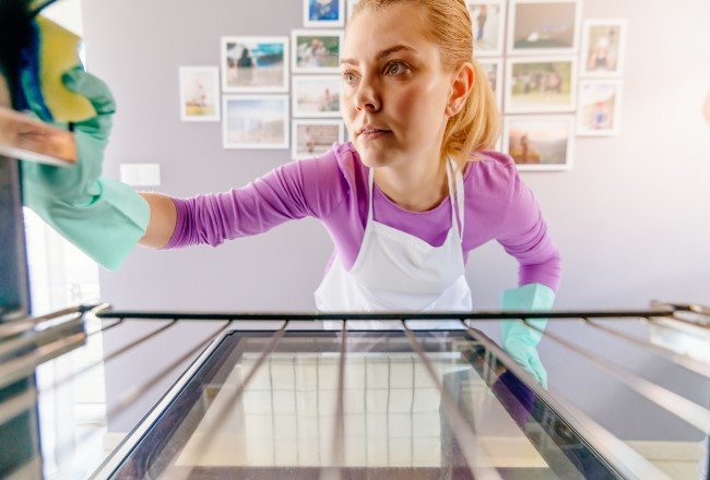 How to clean an electric oven woman cleaning oven front view