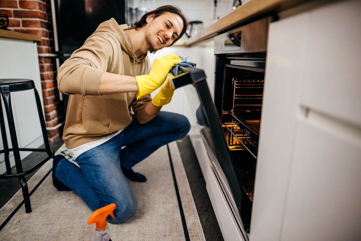 how-to-clean-an-electric-oven-young-man-cleaning-oven.jpg