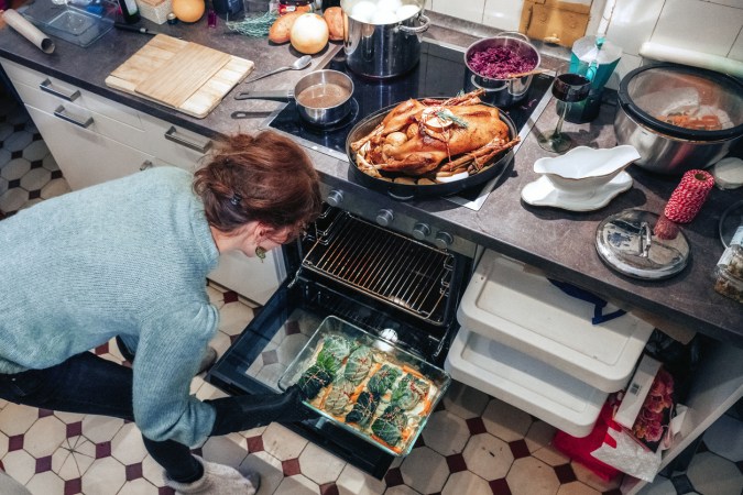 iStock-1420791890 how to clean an electric oven woman cooking big meal in kitchen overhead shot.jpg
