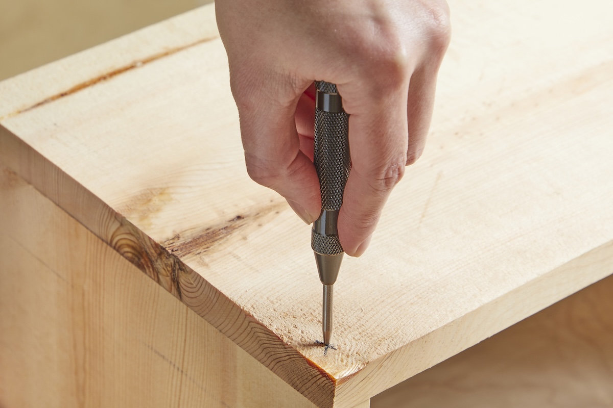 Person marks pilot hole spot with awl.
