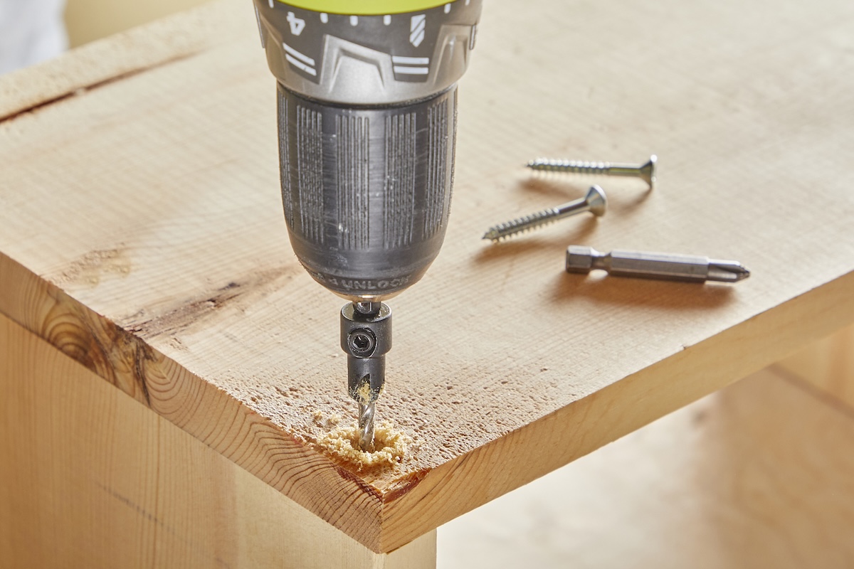 Closeup of a drill making a pilot hole into a piece of wood.