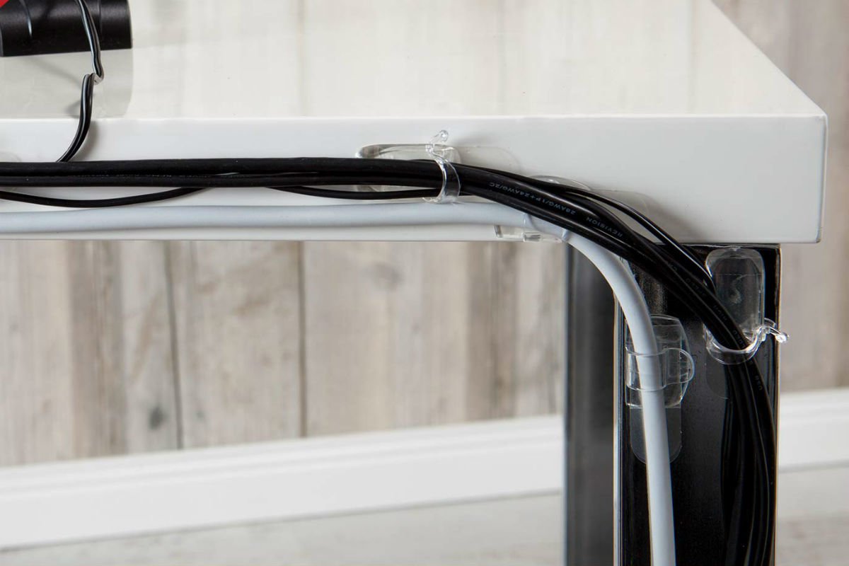 Computer cords neatly tied behind a white desk.