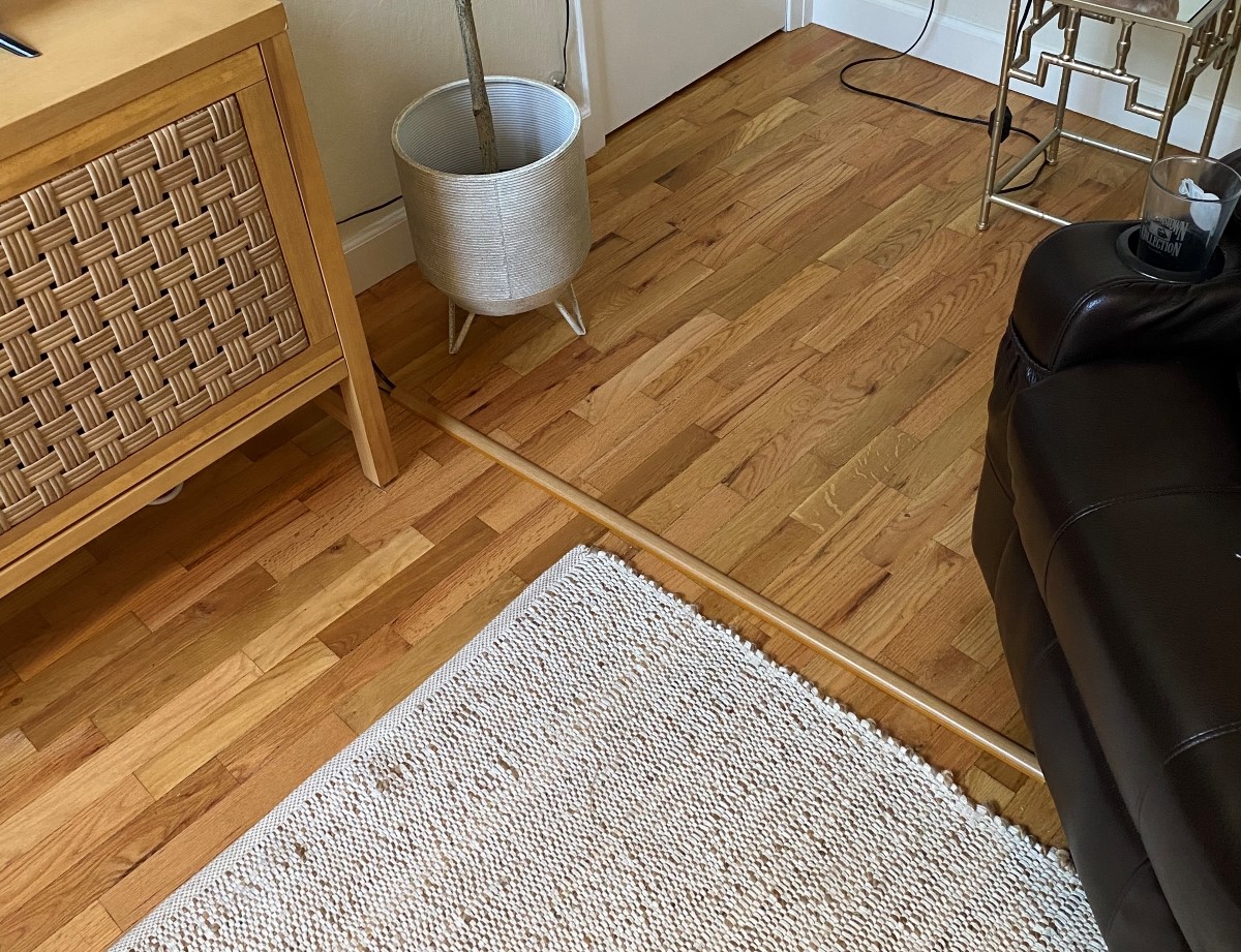 Brown cord hiding cable on wooden floor.