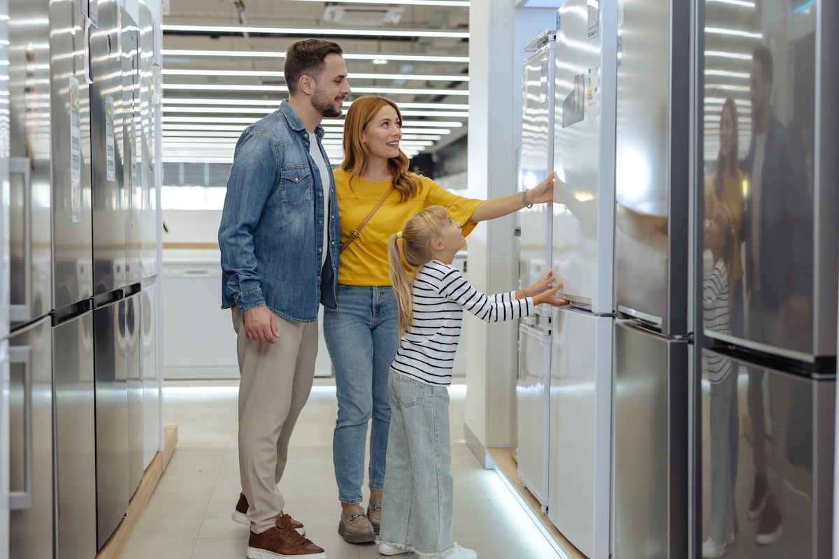A family in an appliance store, looking at a new refrigerator.