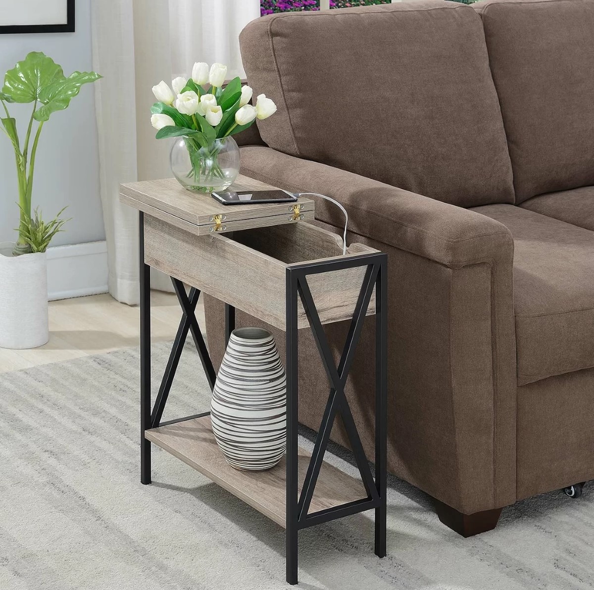 Side table with phone charger inside next to a brown sofa.