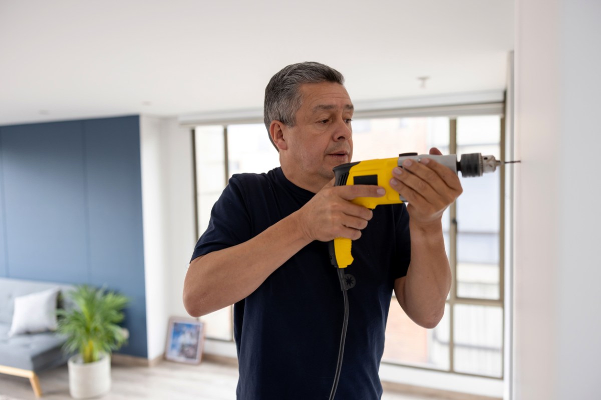 iStock-1408152940 how to use drywall anchors man drilling into wall