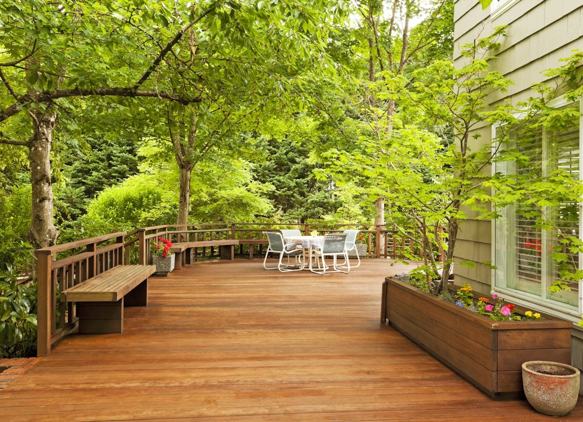 View of large wooden deck with surrounding green trees.