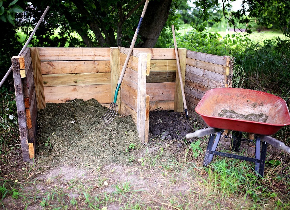 View of wooden composter in yard.