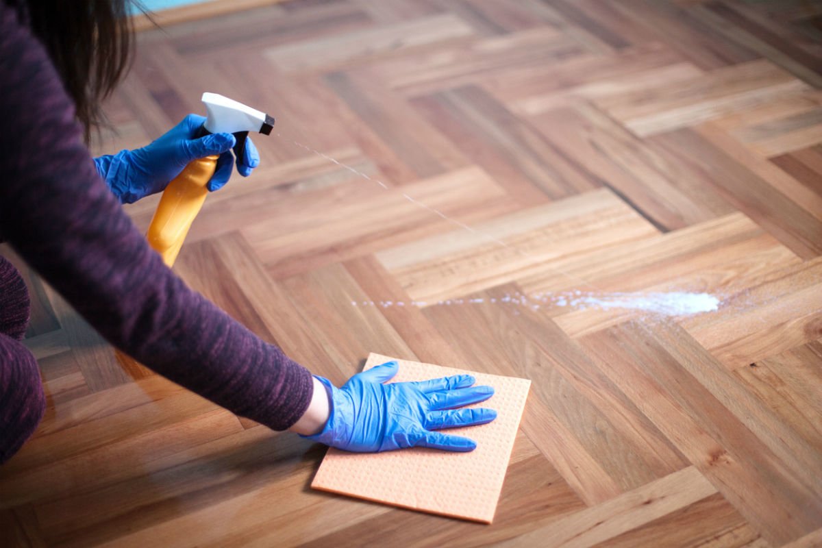 A person using the best hardwood floor cleaner option and a microfiber towel to clean a hardwood floor