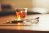 A glass of amber liquor and a cigarette in an ashtray sit atop a a wooden table.