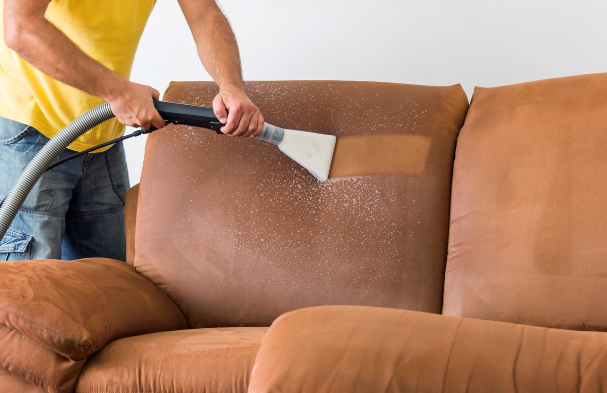 Person using vacuum to deep clean couch