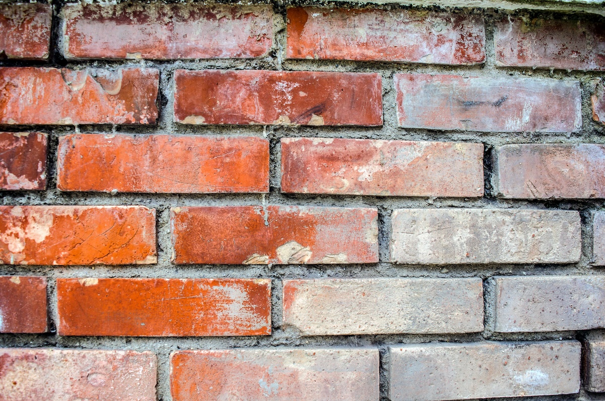 A brick wall with white stains from water.