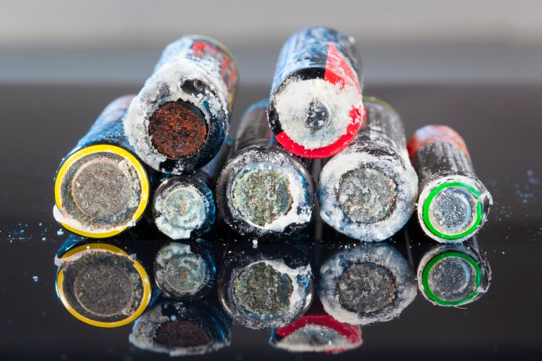 Different kinds of corroded batteries stacked on top one another.