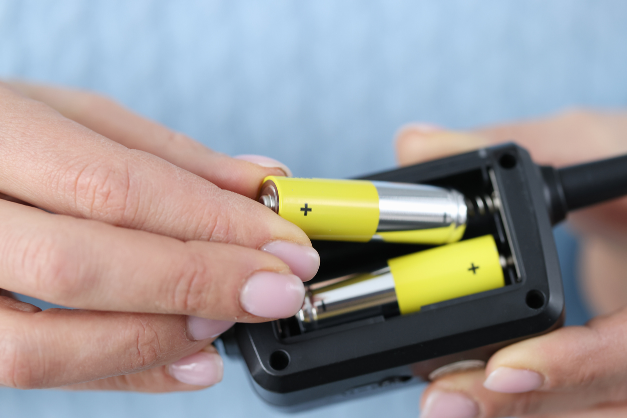 Woman with pink nail polish changes batteries in remote.