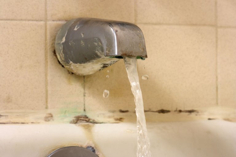 A bathtub faucet with lime scale buildup.