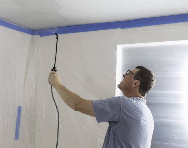 Man spraying ceiling before popcorn ceiling removal