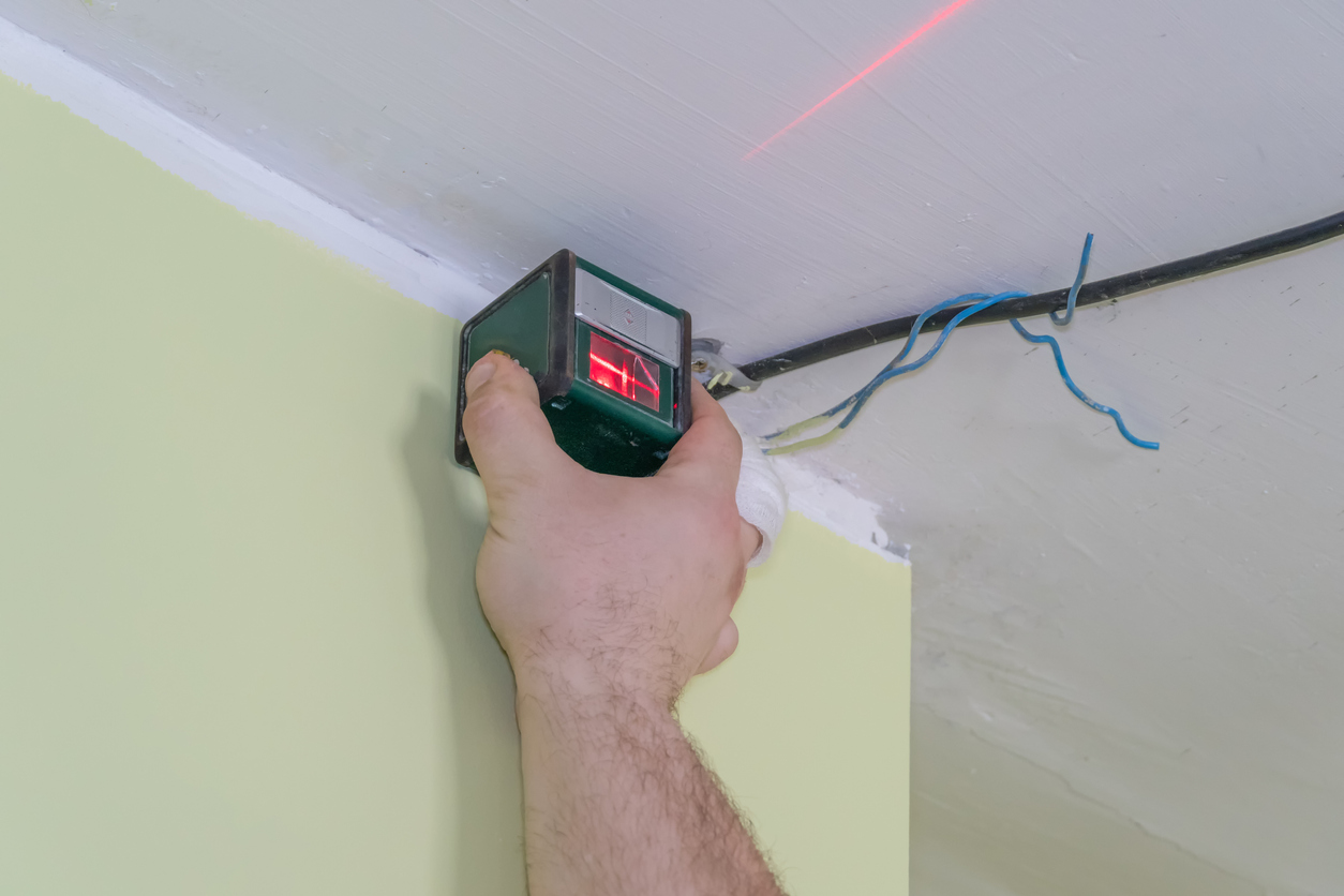 Marking the wall with a laser level for installation of a stretch ceiling. Red light on the wall.