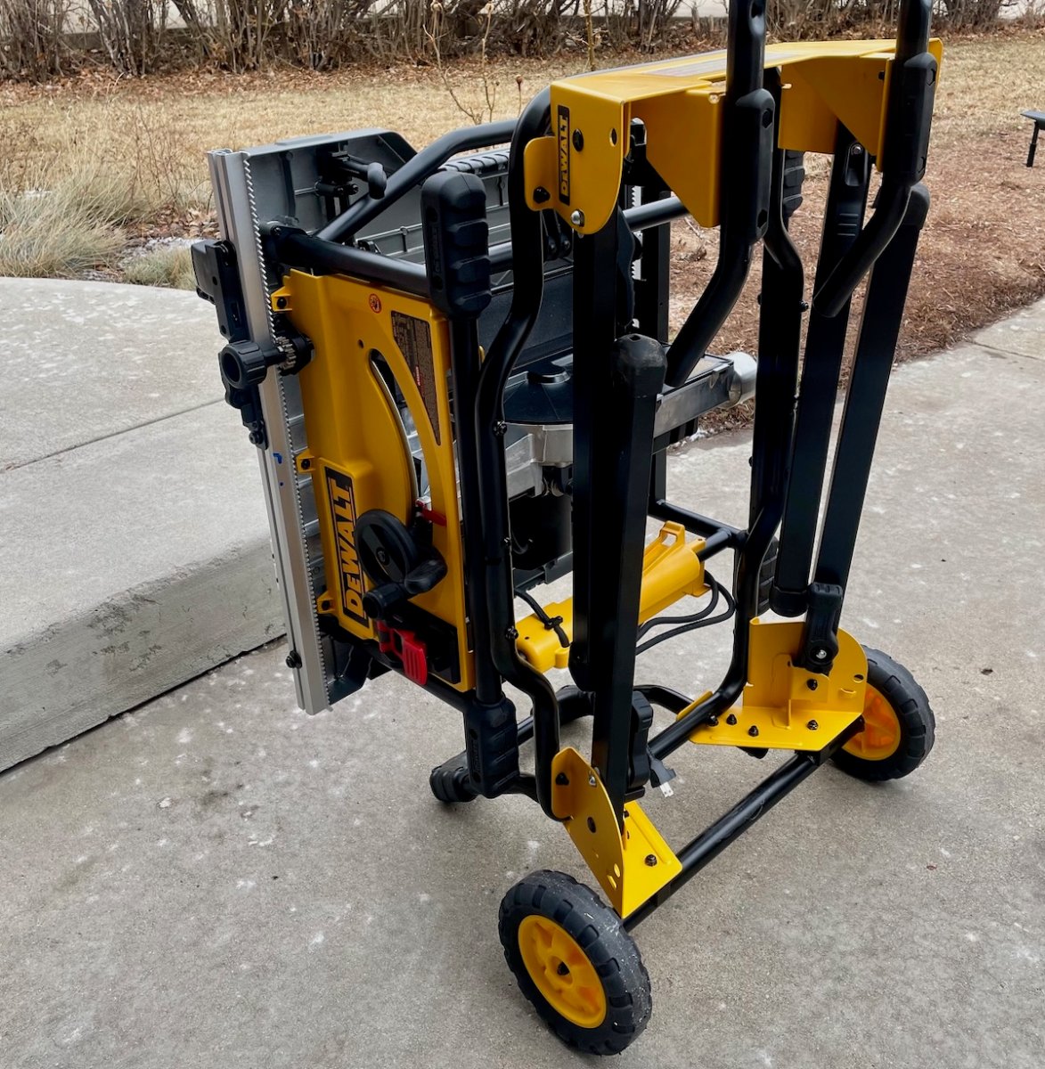 DeWalt table saw folded on an outdoor concrete walkway.