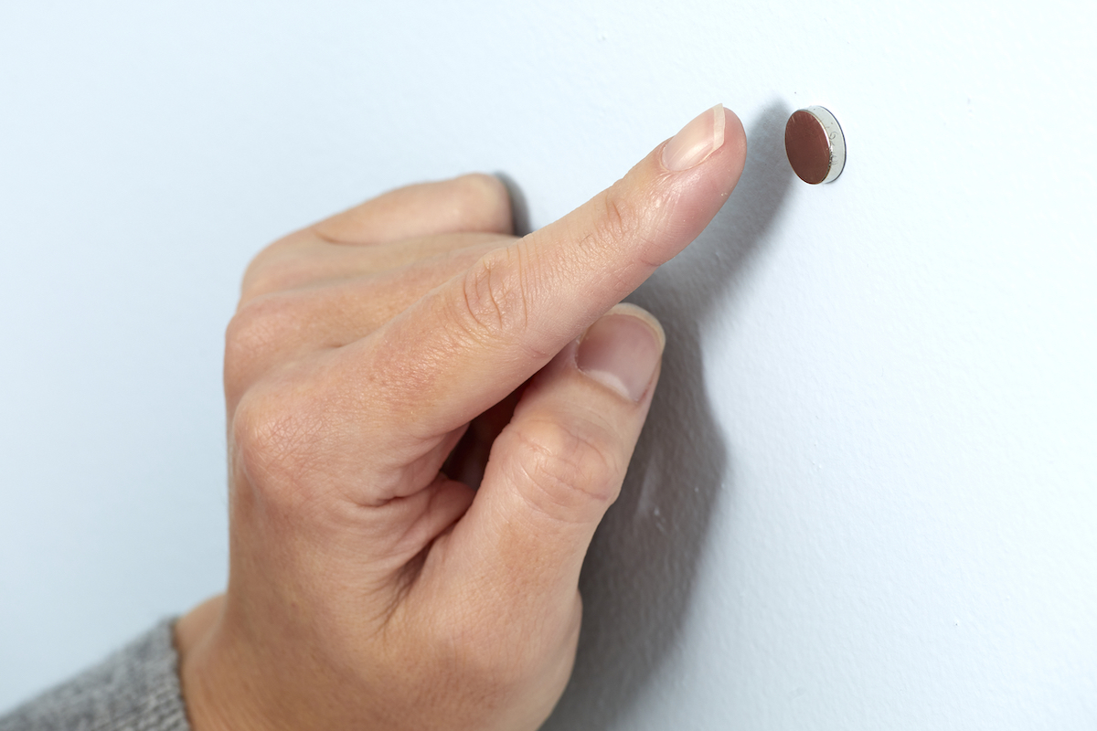 Woman points to a small magnet on the wall.