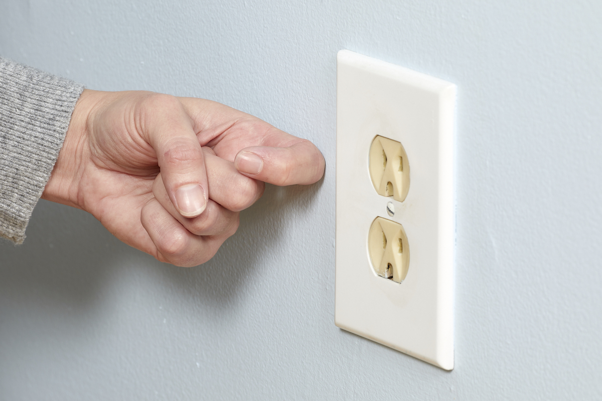 Woman knocks on the wall next to an electrical outlet.