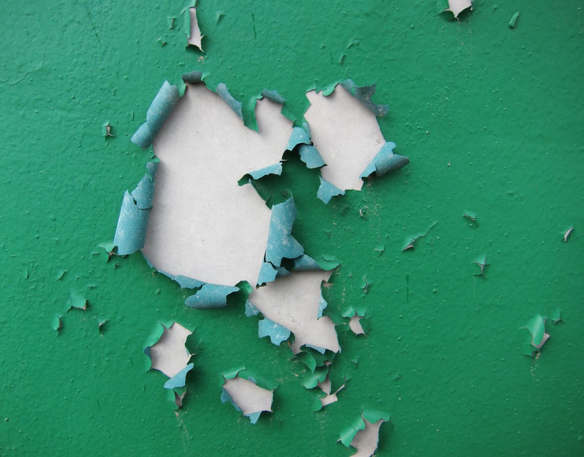 Green paint peeling off a metal surface.