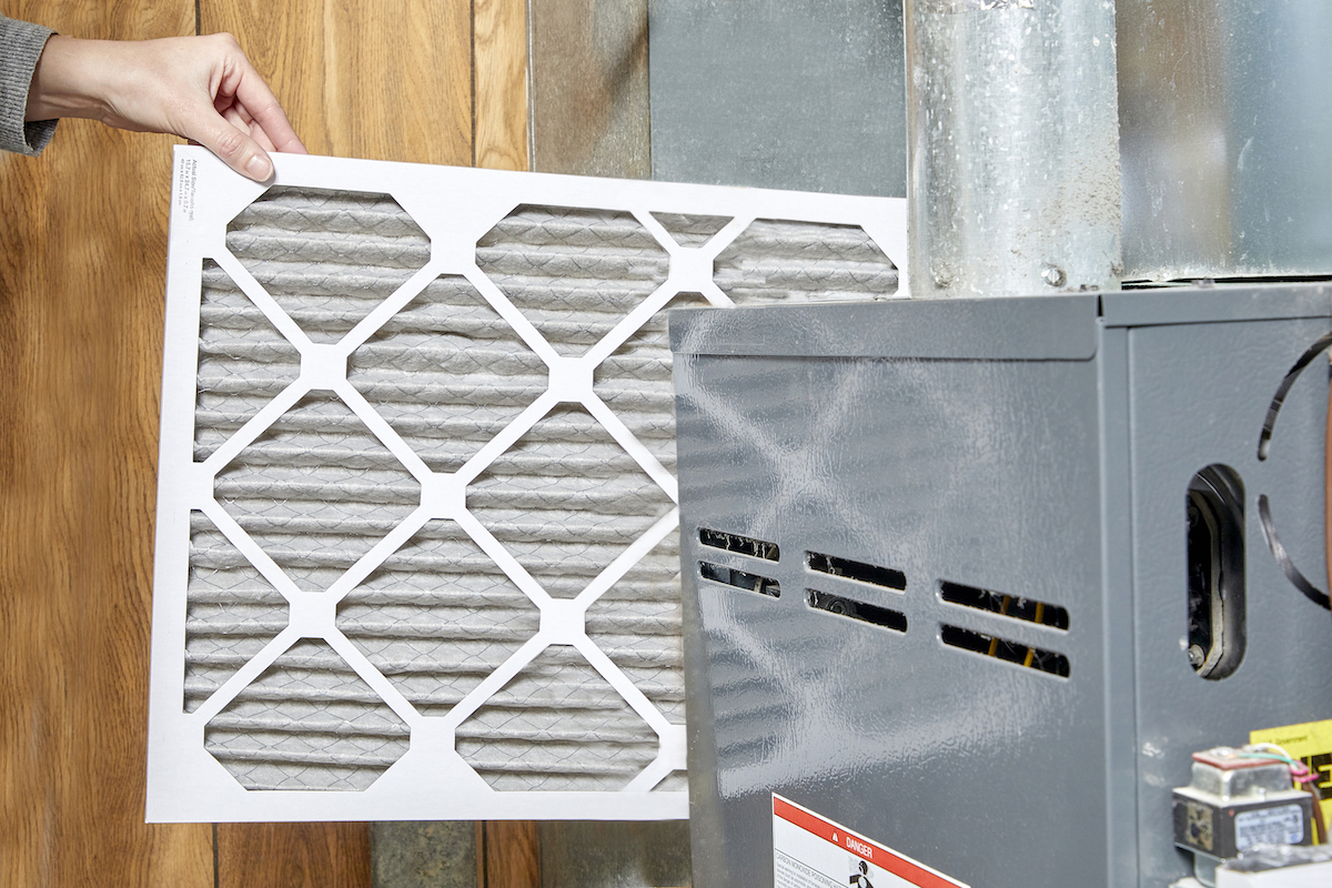 Woman inserts new filter into her furnace.