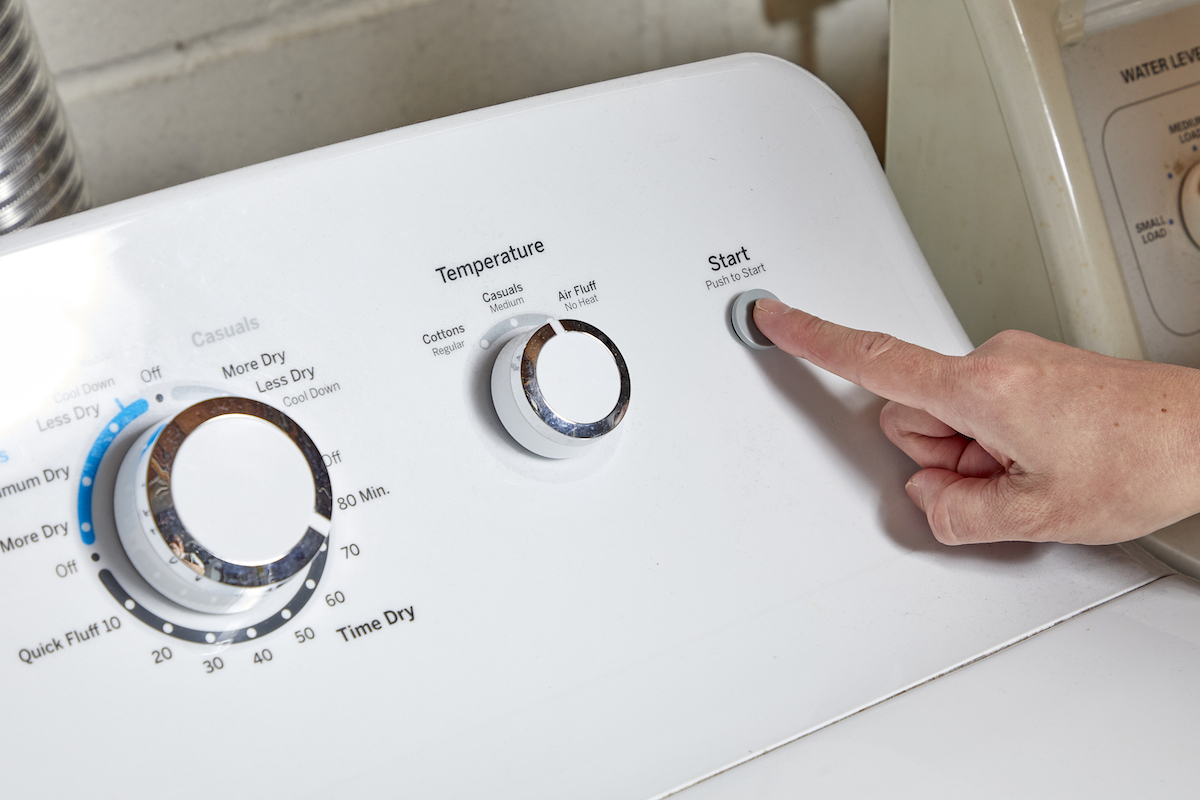 Woman pushes the "start" button on her clothes dryer.