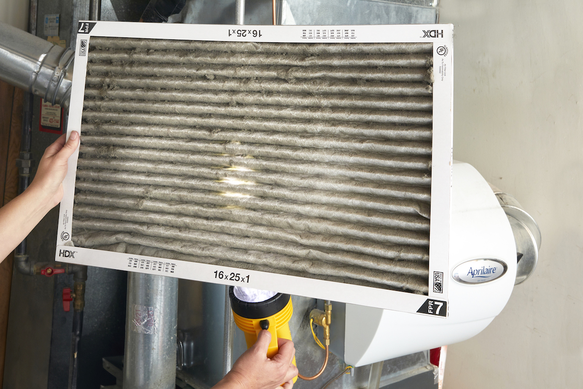 Woman holds up a dirty pleated furnace filter.
