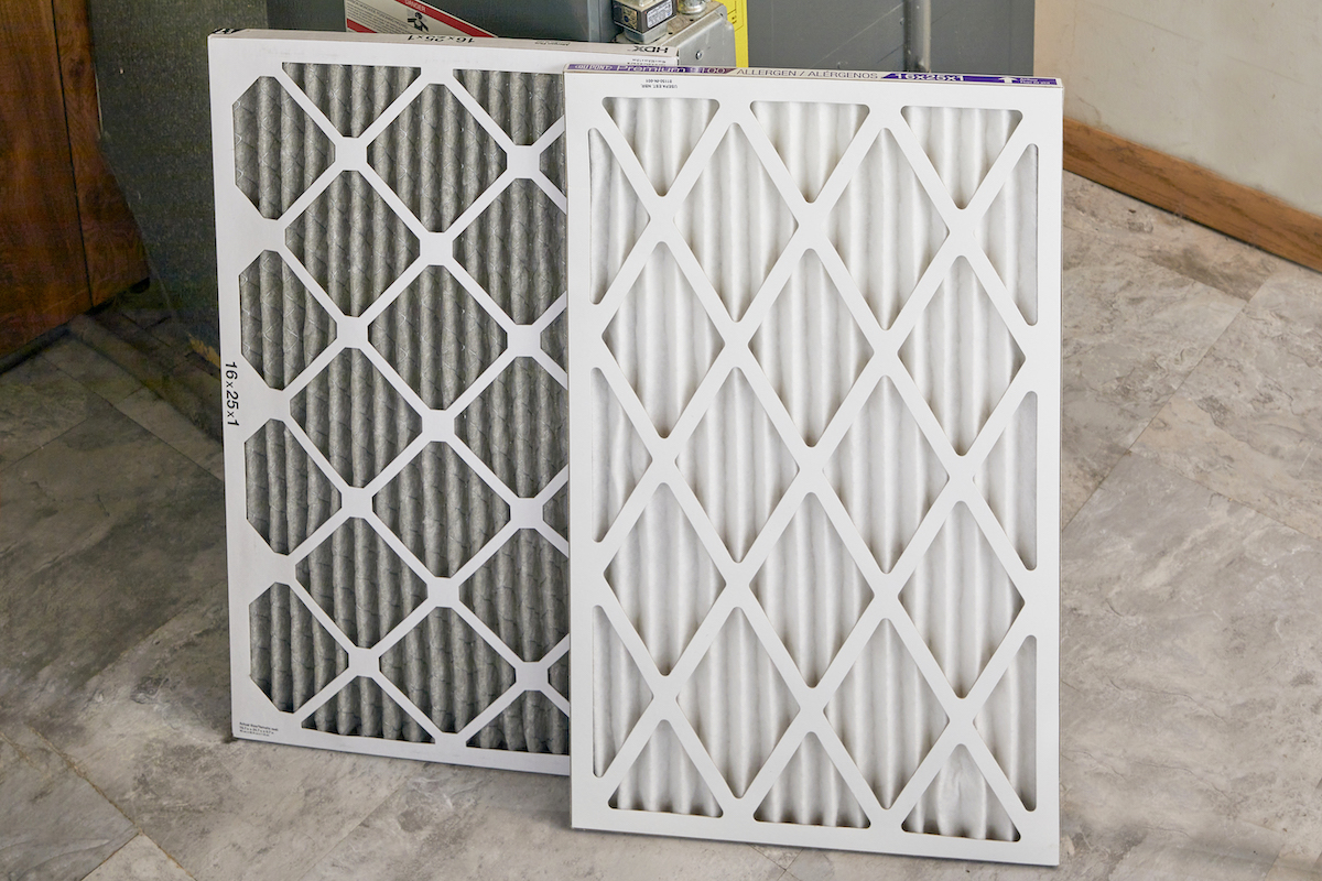 A used and a new furnace filter, propped side by side.