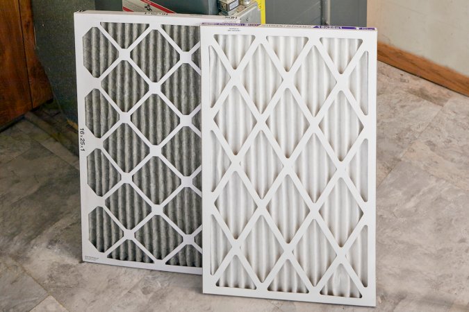 A used and a new furnace filter, propped side by side.
