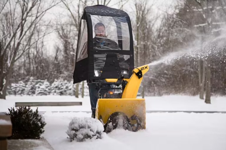 Man using the Arnold Snow Blower Cab attachment while blowing snow off his driveway.