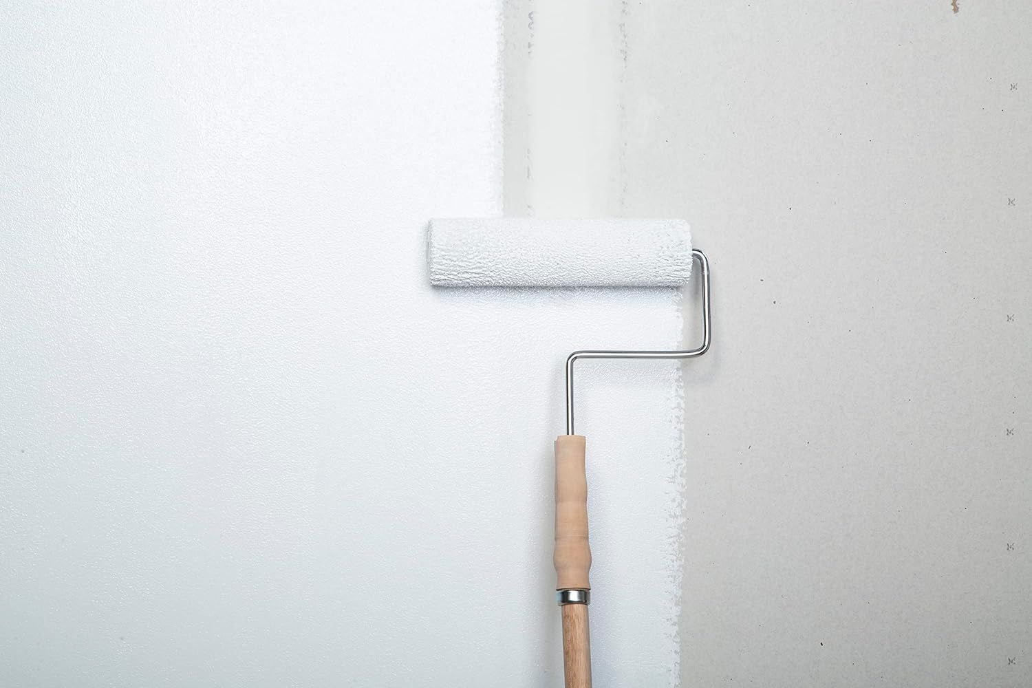 Painter using the best paint primer for a smooth wall finish.