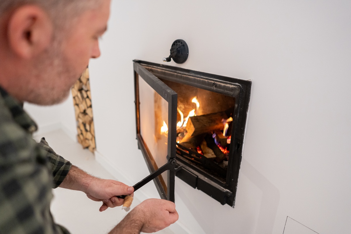 A man opens up a fireplace damper.