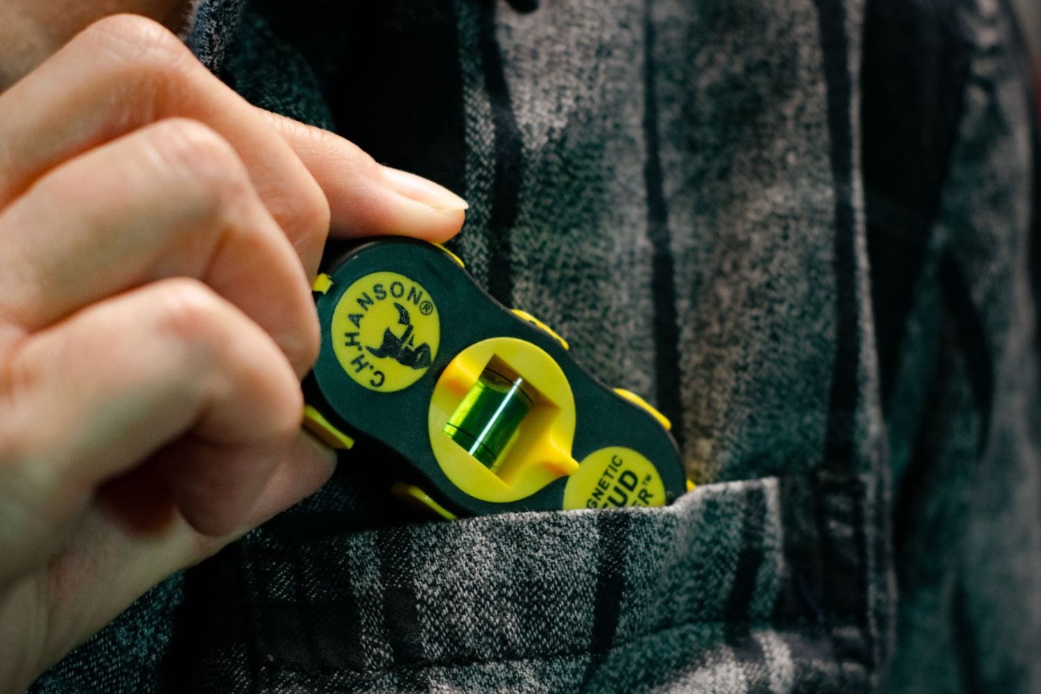 Someone pulling the small C.H. Hanson 03040 Magnetic Stud Finder out of their shirt pocket.