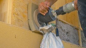 Blown-in insulation being installed into a wall using a hand-held pump.