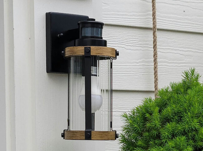 Decorative wood and metal motion sensor light installed on a house.