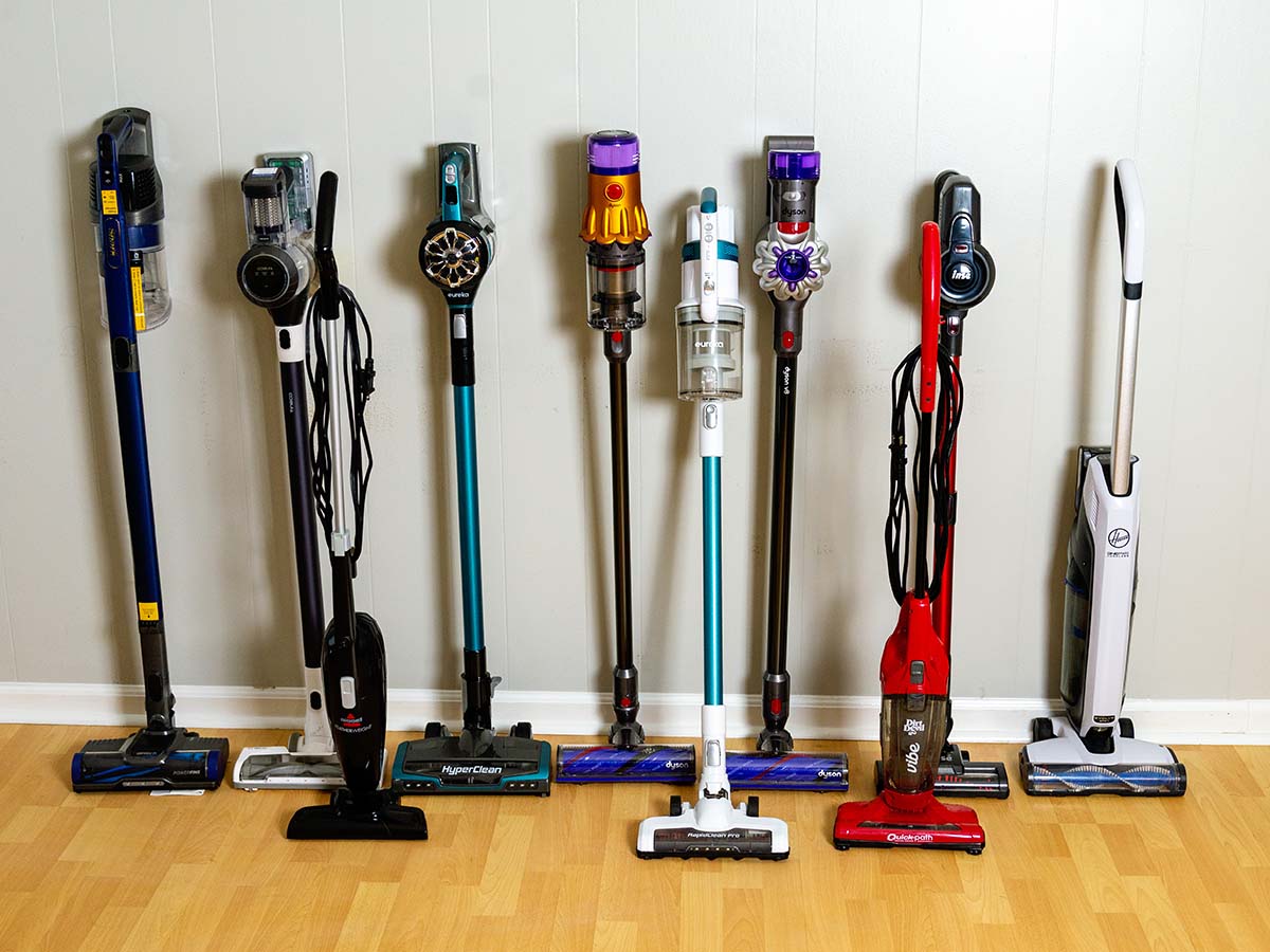 A group of the best stick vacuums together on a wood floor against a wall.
