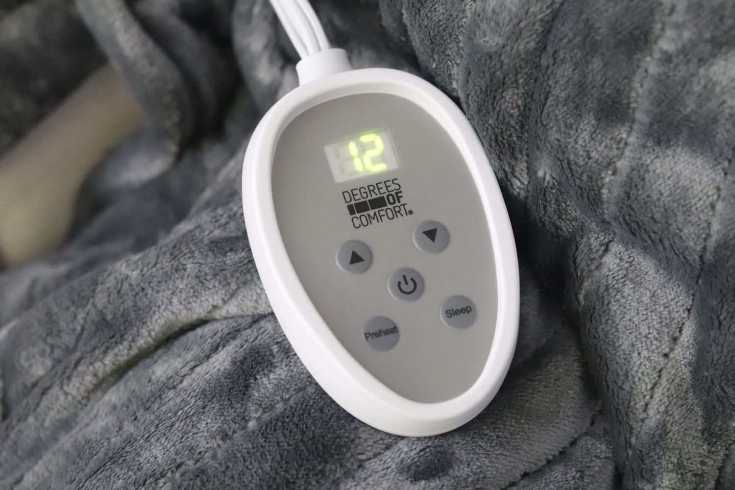 The controller of the best electric blanket on top of the blanket showing a heat setting of 12.