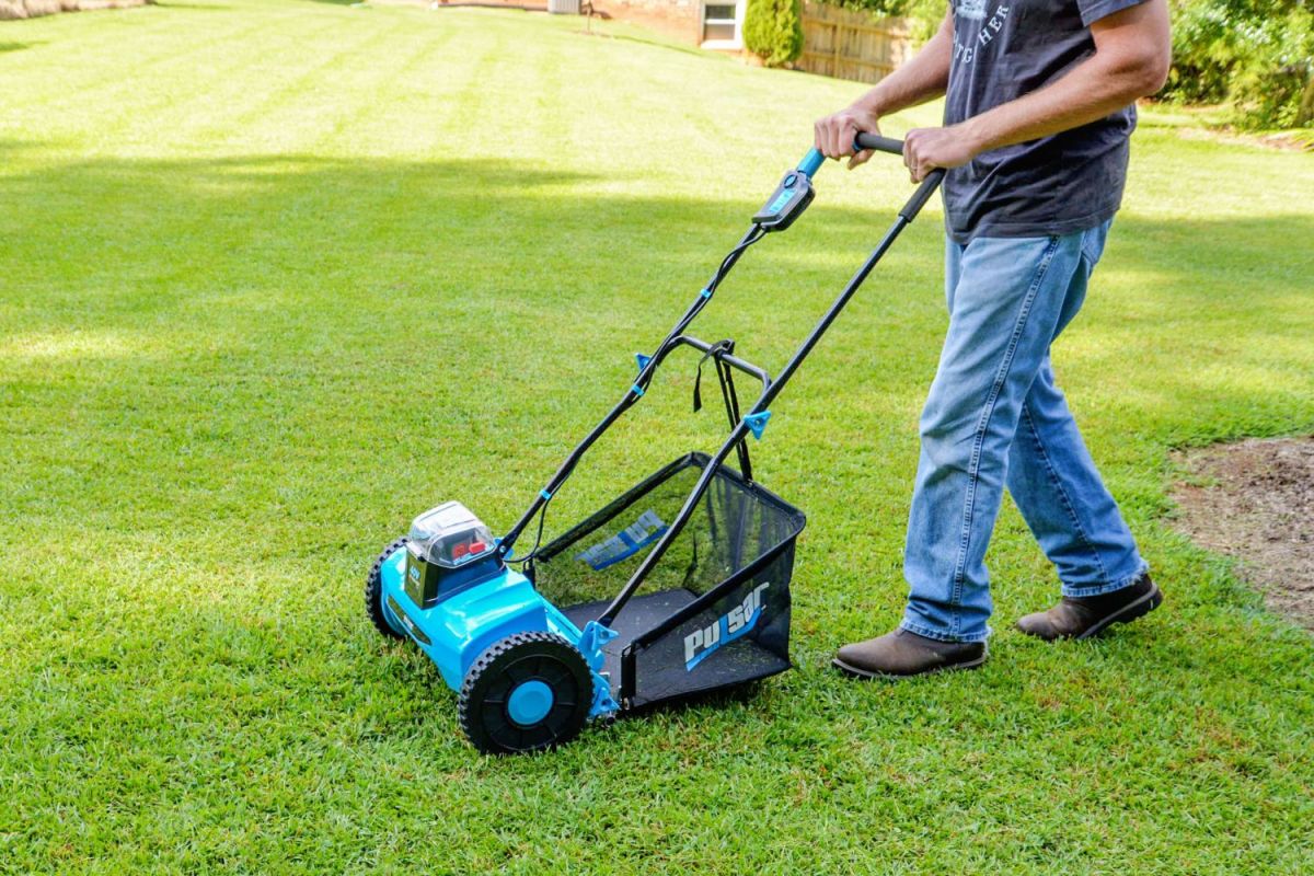 A person using the best reel mower to mow a large lawn.