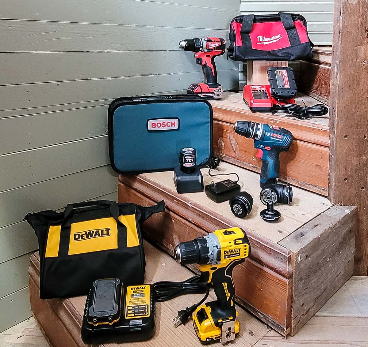 A group of the best cordless drill options sit with their cases and batteries on a set of wooden stairs