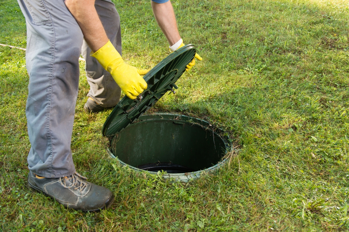 Person pulling open septic tank lid