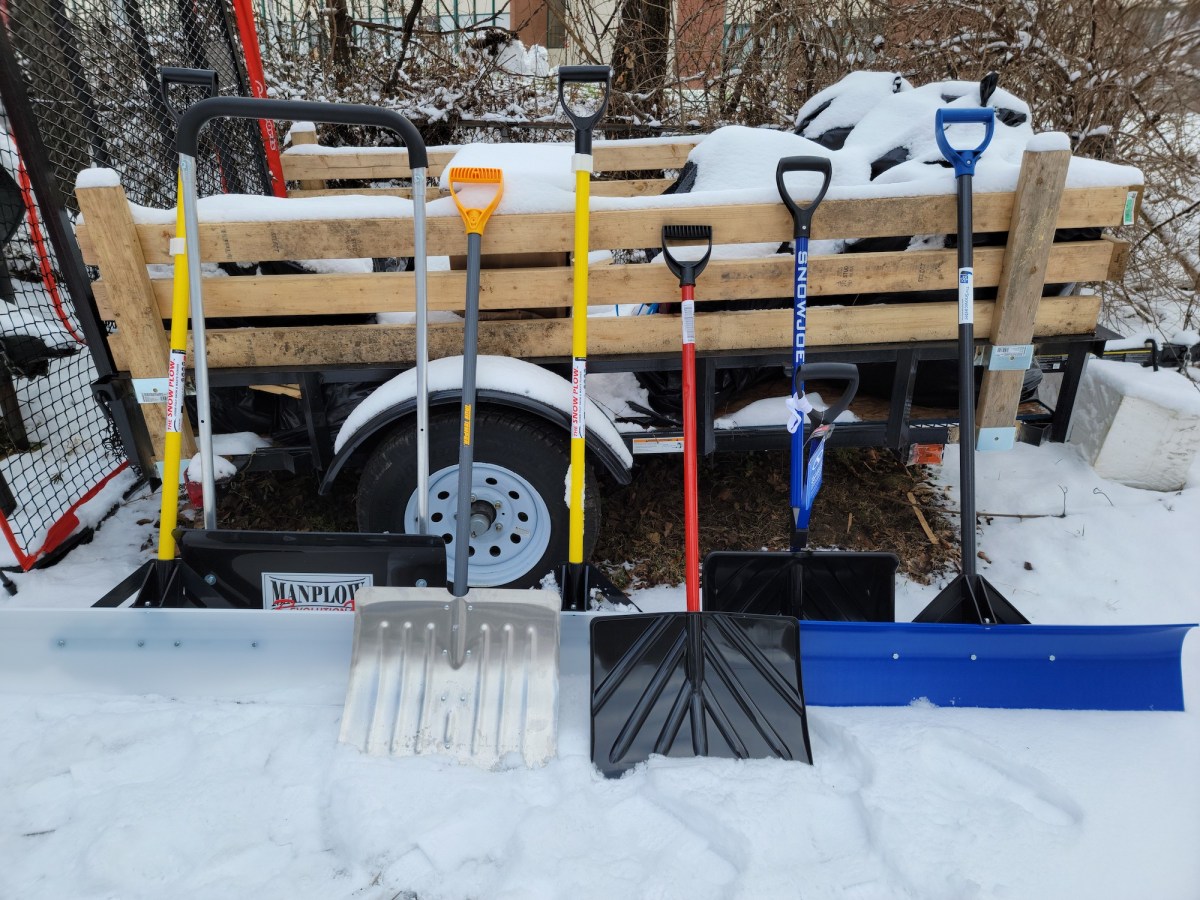 A group of the best snow shovel options leaning against a trailer in the snow before testing.