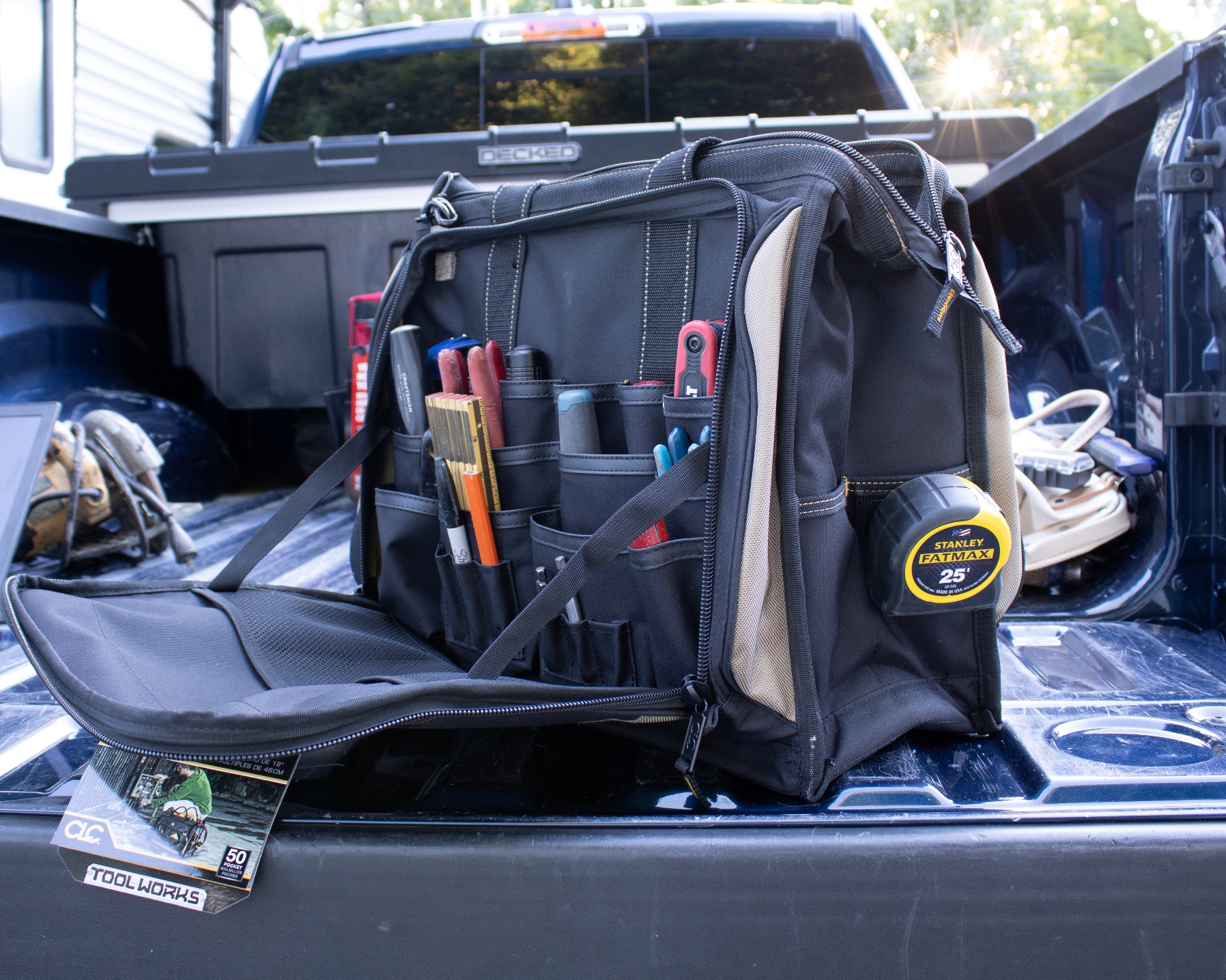 The top tested tool bag in the back of a pickup and open to reveal a full set of tools.