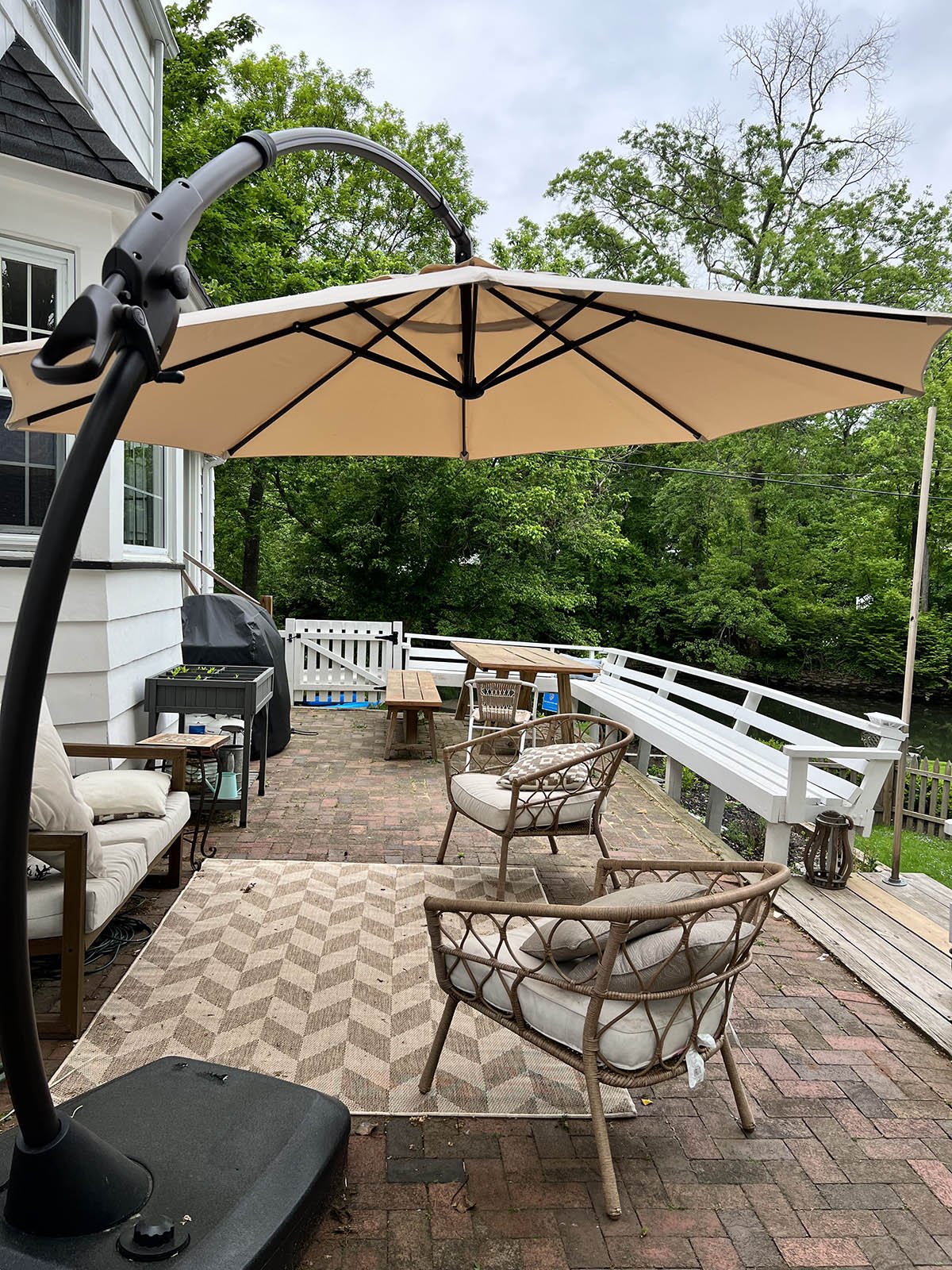 The best patio umbrella option set up in the corner of a deck to provide shade for two outdoor chairs and a couch