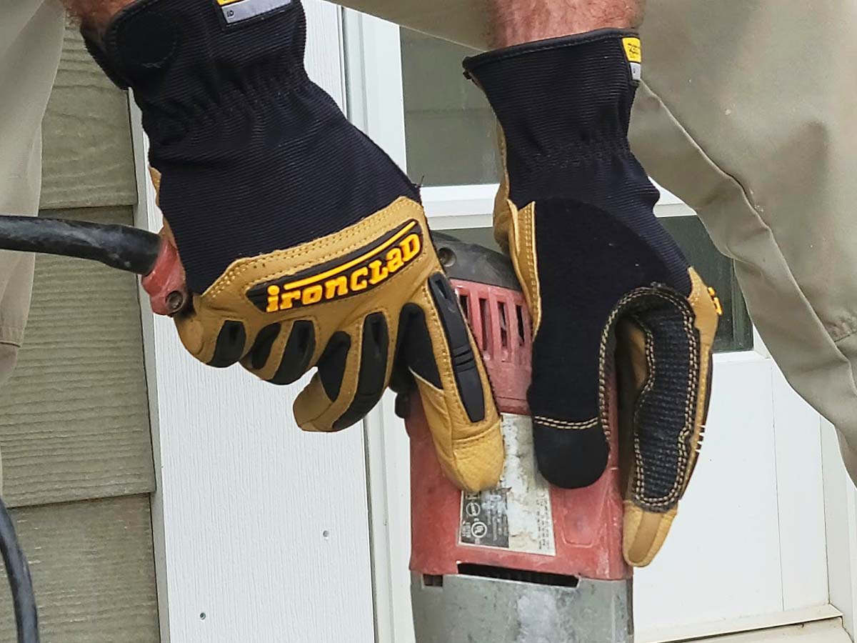 A person wearing the Ironclad Ranchworx Work Gloves while operating a corded power tool.